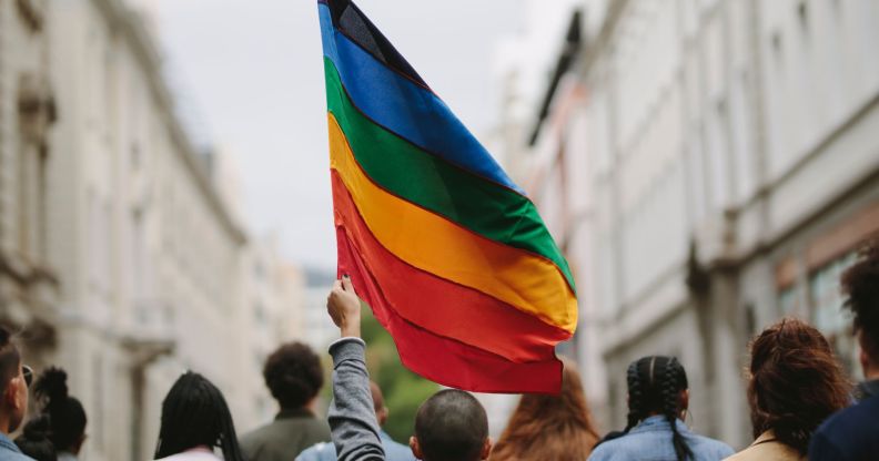 A protest group, with one person holding a Pride flag.