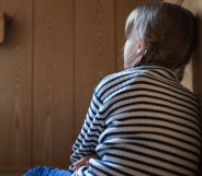 A young person leaning against a kitchen cabinet.