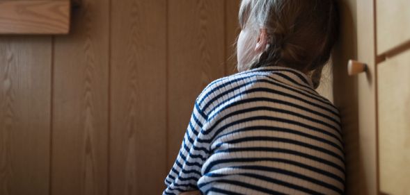 A young person leaning against a kitchen cabinet.