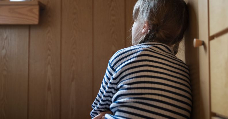 A young person leaning against a kitchen cabinet.