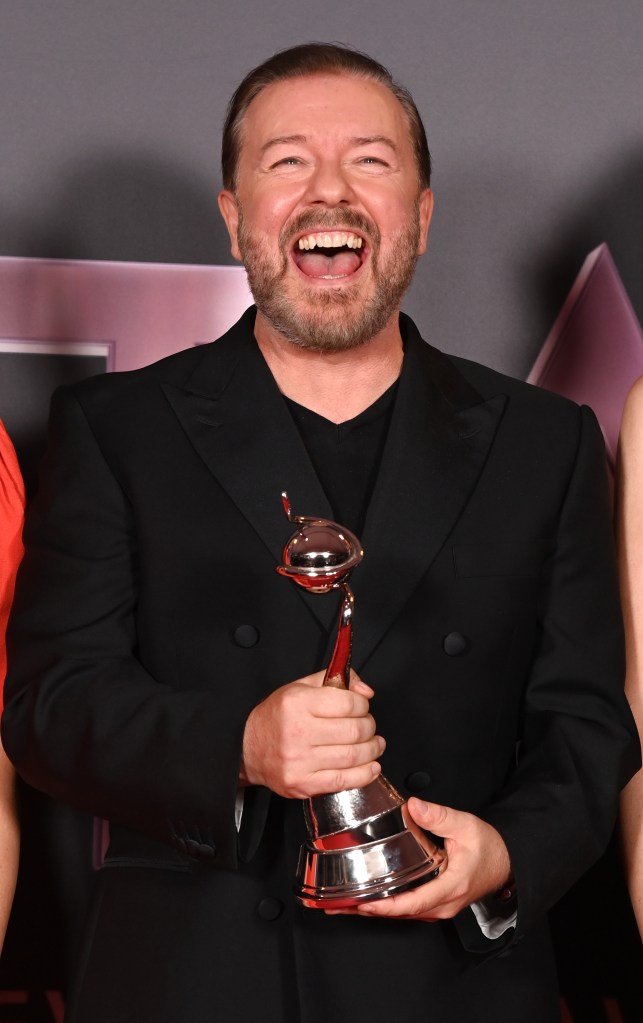 Ricky Gervais smiling with a golden globe