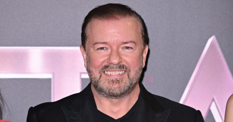 Ricky Gervais in all black suit smiling at the camera