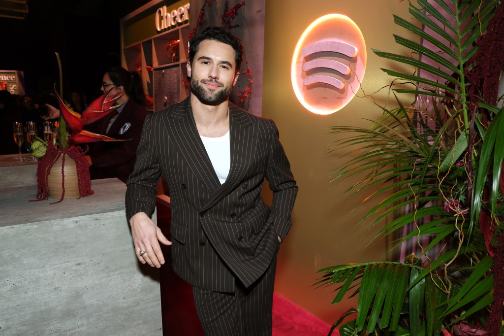 Robbie GK smiling in a dark brown pinstripe suit