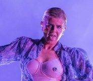 Robyn performing with a floral shirt open to reveal a bejewelled bra