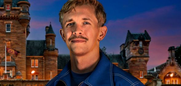 Stephen in front of The Traitors castle in a blue jacket