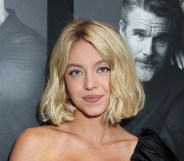 Sydney Sweeney smiling at the camera, wearing a black dress