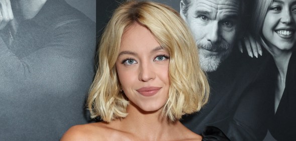 Sydney Sweeney smiling at the camera, wearing a black dress