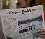 A person holding a copy of the New York Times paper.