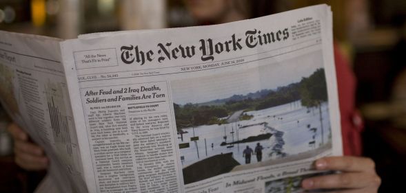 A person holding a copy of the New York Times paper.
