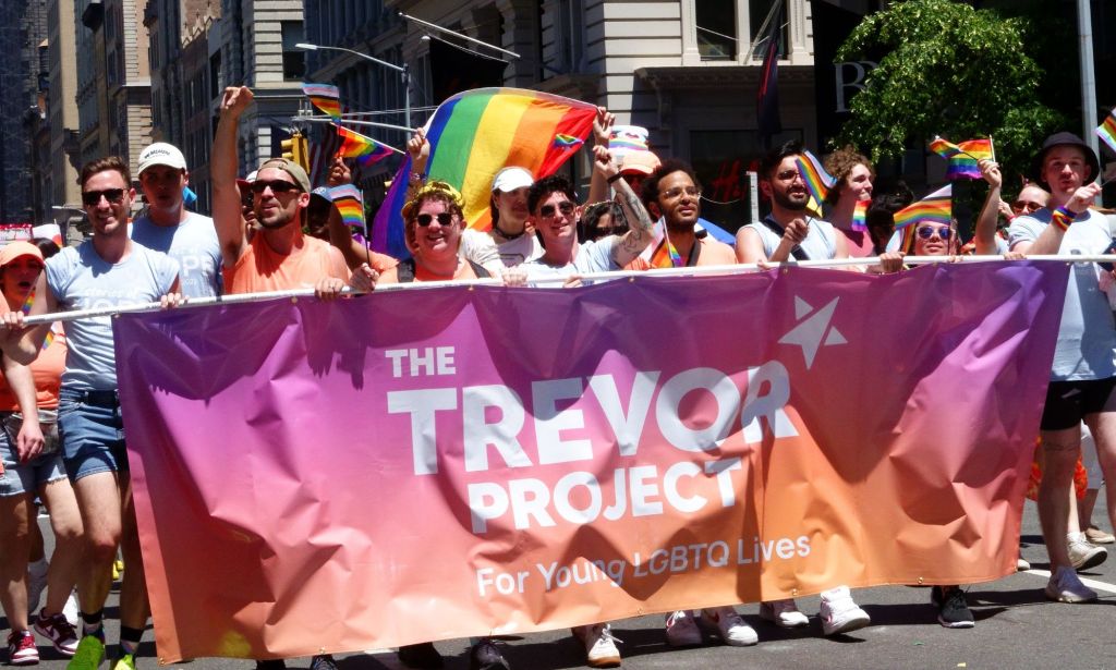 A crowd of people holding a banner for The Trevor Project during a Pride march.