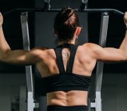 A woman using a pull-up machine at the gym.