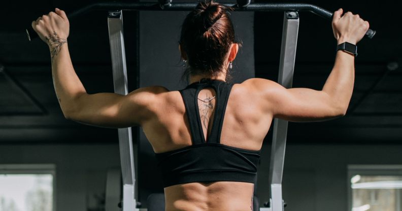 A woman using a pull-up machine at the gym.