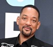 Will Smith at the 67th GRAMMY Awards. Wearing a black suit against a grey backgrop