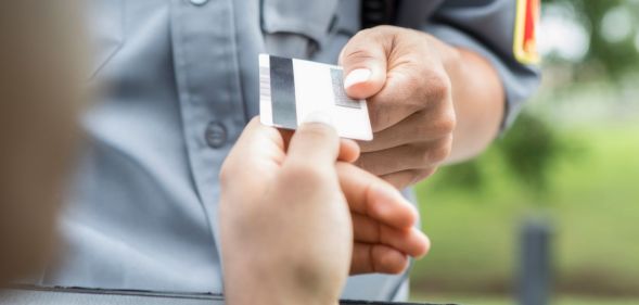 A person handing an officer their license.