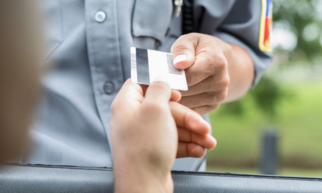 A person handing an officer their license.