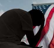 A distressed man in silhouette sits in dark room texting on smartphone. Blinds drawn in window light making silhouette of man with hand of forehead communicating on cell phone. Moody dark image with copy space.