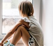 A child sat looking out of a window.