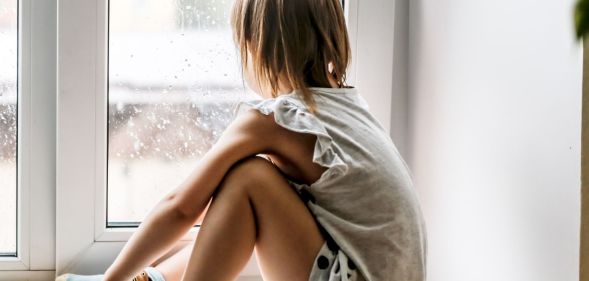 A child sat looking out of a window.
