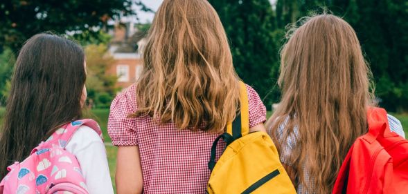 The back profile of three primary-age students.