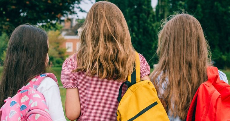 The back profile of three primary-age students.