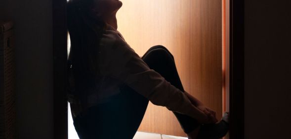 A young person sat pensively in a doorway.