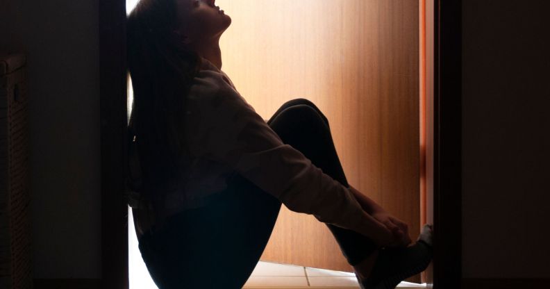 A young person sat pensively in a doorway.