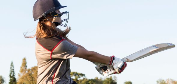 Someone swinging a cricket bat.