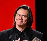 Jim Carrey in a full black suit receiving his award at the Cesar Film Awards.