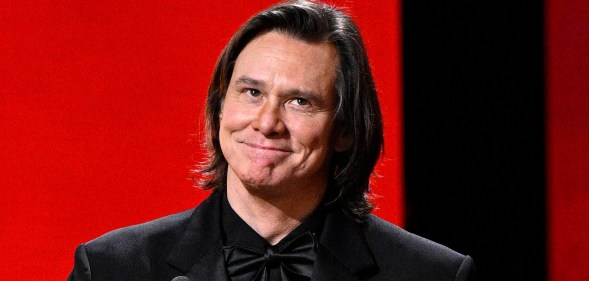 Jim Carrey in a full black suit receiving his award at the Cesar Film Awards.