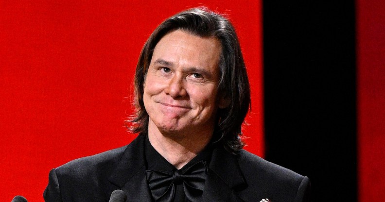 Jim Carrey in a full black suit receiving his award at the Cesar Film Awards.