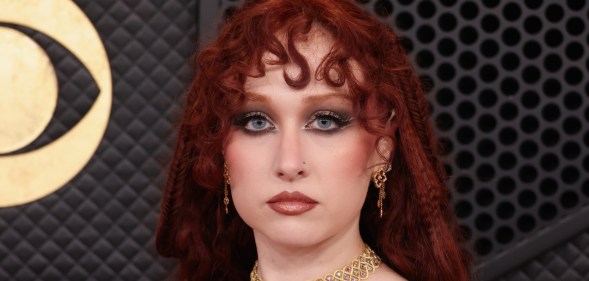 Chappell Roan attends the 68th GRAMMY Awards, wearing a gold choker and a red hood over her hair