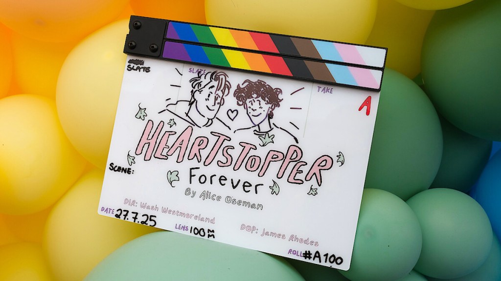 Film clapperboard of Heartstopper forever by alice oseman on top of rainbow balloons