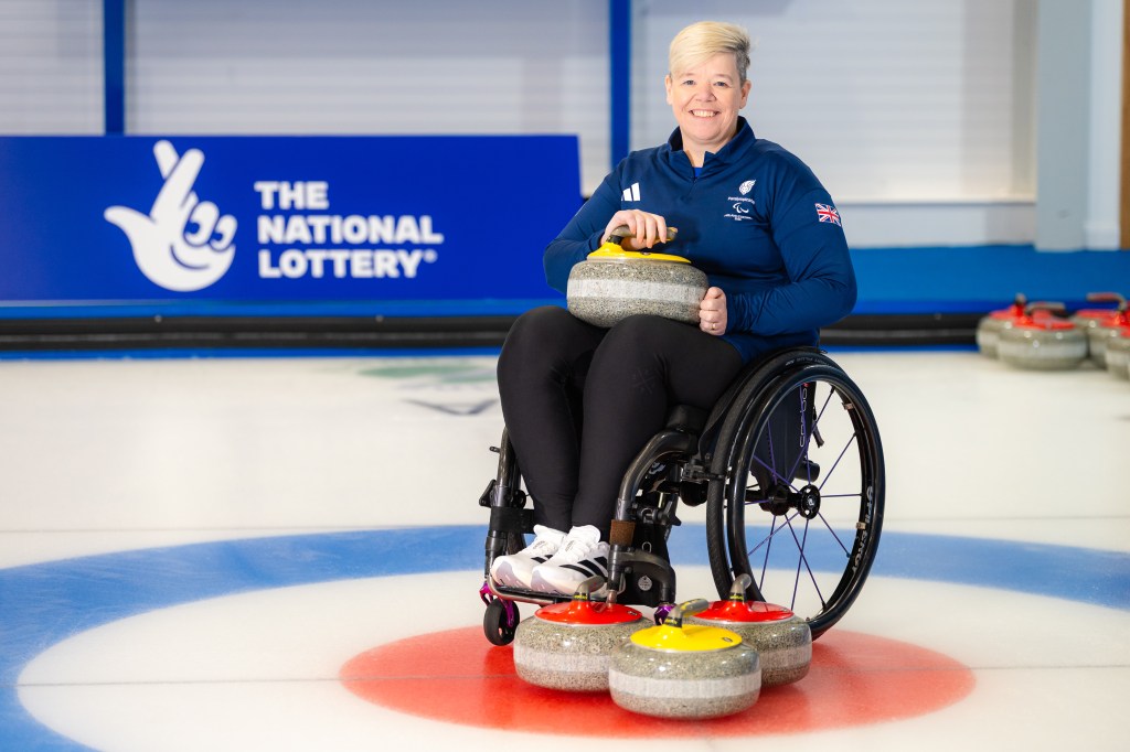 Jo Butterfield in a wheelchair with curling gear on the floor and on her lap.