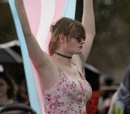 A protestor holds up a trans flag.