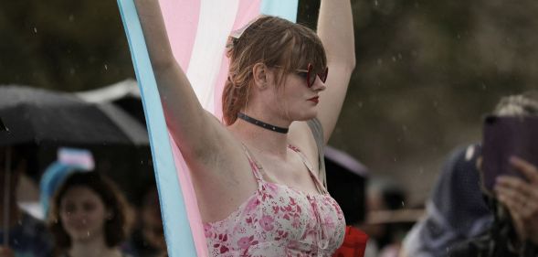 A protestor holds up a trans flag.