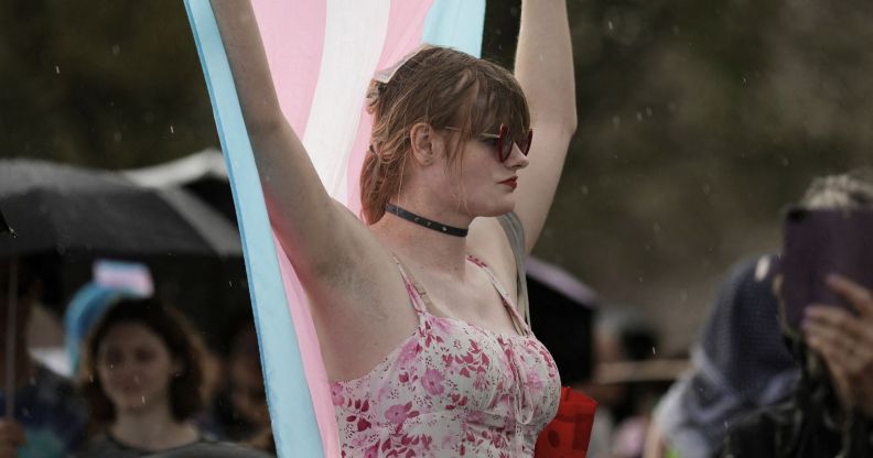 A protestor holds up a trans flag.