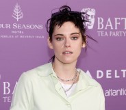 Kristen Stewart in a pale yellow shirt and two silver chain necklaces against a purple BAFTA backdrop