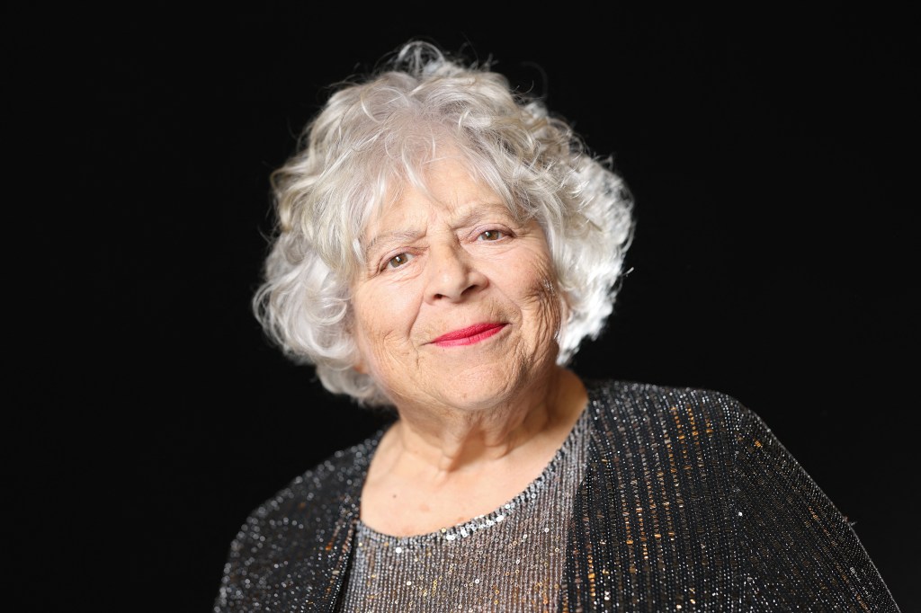 Miriam Margolyes poses during a photo session ahead of the 98th Oscars Nominees. SHe's wearing a sequin grey top and a gdark grey glittery cardigan