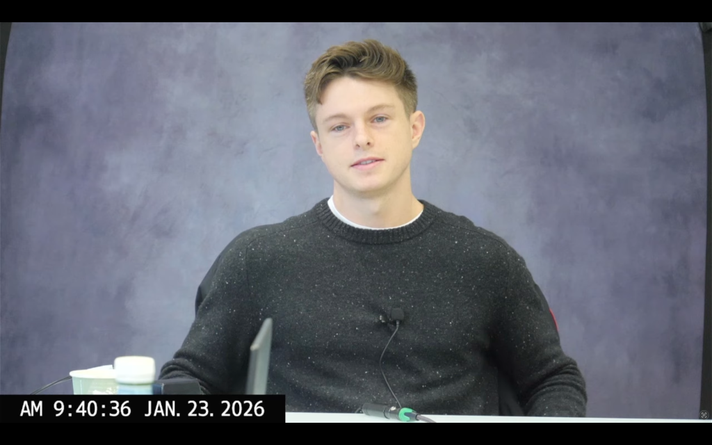 Nathan Cavanaugh's testimony: sat against a grey background, he's wearing a dark grey jumper