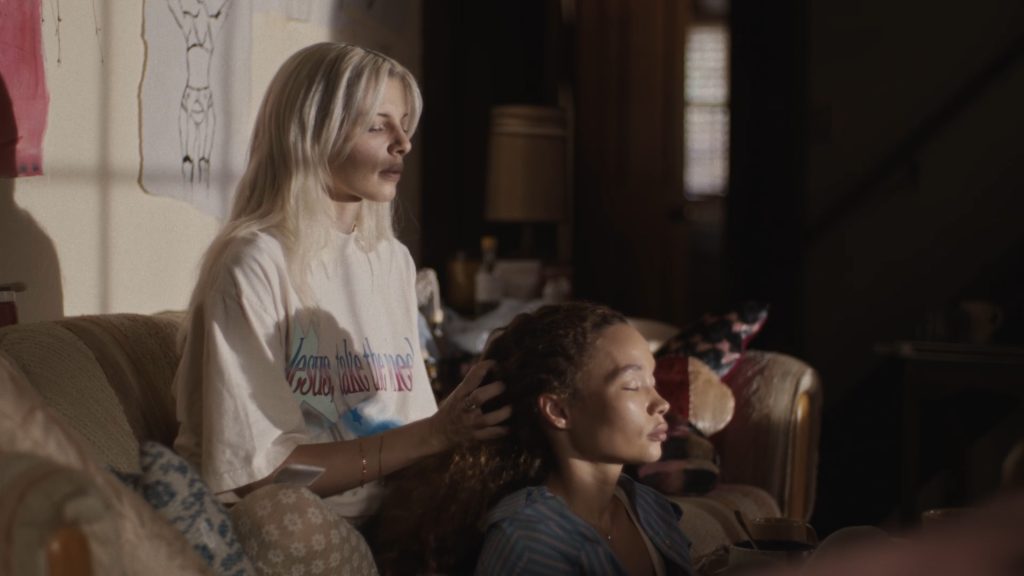 Perfect still: julia fox sat on a sofa, her hands in Ashley Moore's hair