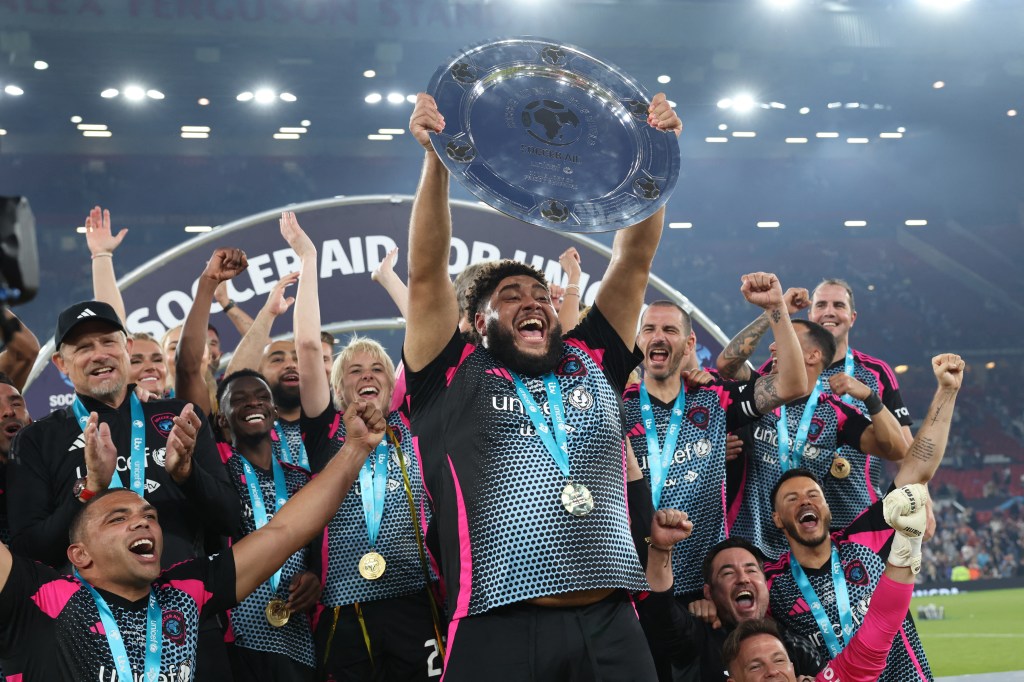 British television presenter Zuhair Hassan known as Big Zuu lifts the trophy as World XI players celebrate their victory in the England XI v World XI charity football match for Soccer Aid for Unicef at Old Trafford in Manchester, north-west England on June 15, 2025.