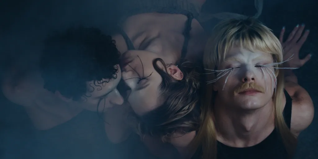 To Dance is to Resist still: three dancers with make up and extremely long eyelashes resting their heads together.