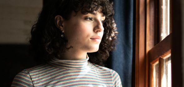 A trans person looking at the window.