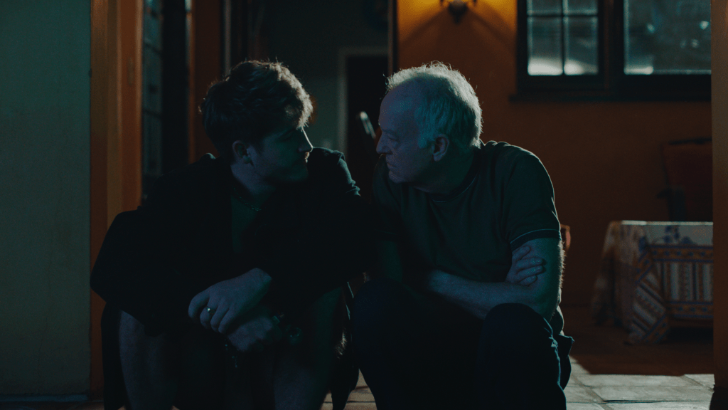 Aaron and Hank sat in the dark outside, leaning towards one another