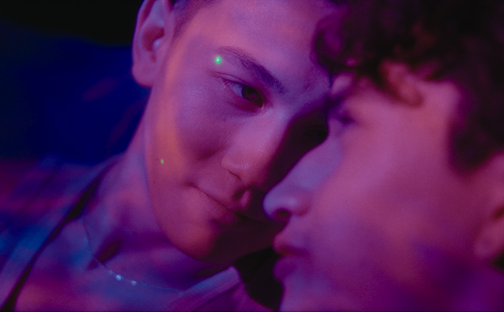 Molly still: two people looking at eachother closely in a close-up with pink lighting