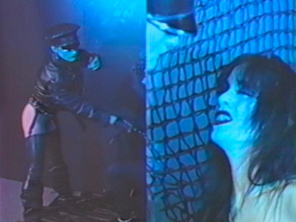 Pixelated Lesbian Mixtape: Azian Nurudin’s Wicked Times still: a person with a whip in the background with a woman in the foreground.