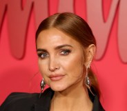 Ashlee Simpson wearing a black blazed and silver drop earrings in front of a red background