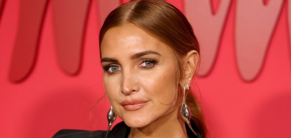 Ashlee Simpson wearing a black blazed and silver drop earrings in front of a red background