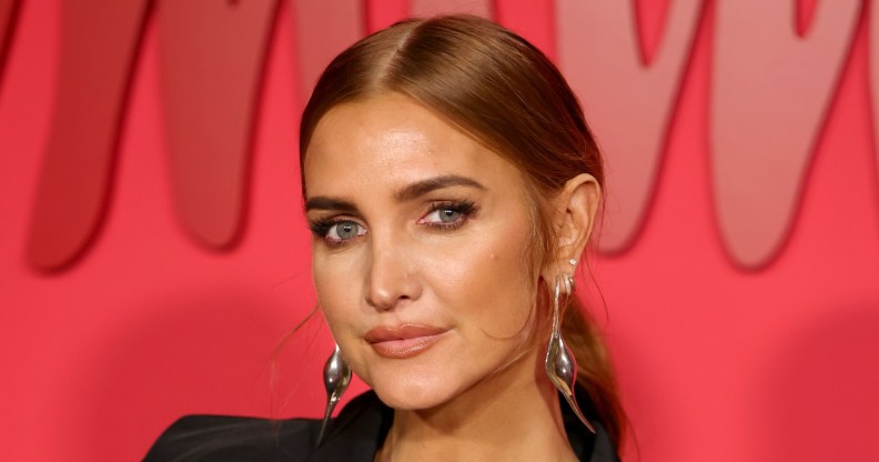 Ashlee Simpson wearing a black blazed and silver drop earrings in front of a red background