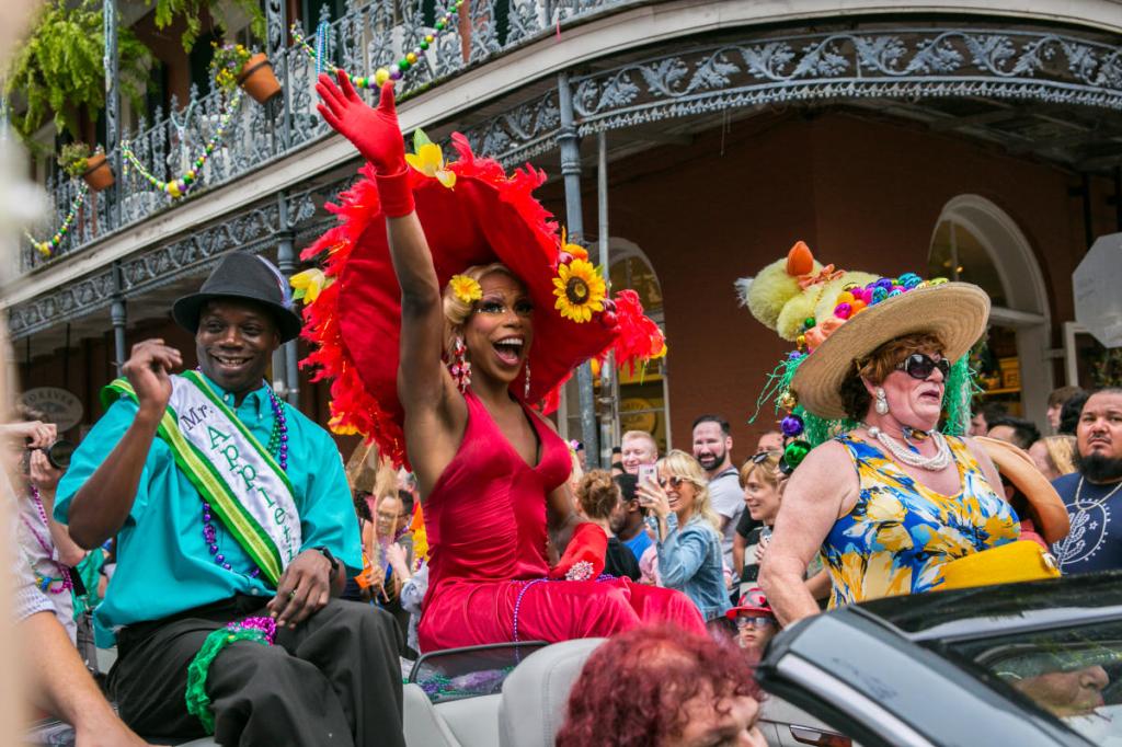 New Orleans Gay Easter Parade image: three individuals in bright coloured outfits in an open-top car